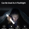 A hand is using a portable flashlight-style LED light to illuminate a person inside a dark cloth.