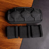 Black multi-slot watch travel organizer case with a comfort pillow resting on a wooden surface.