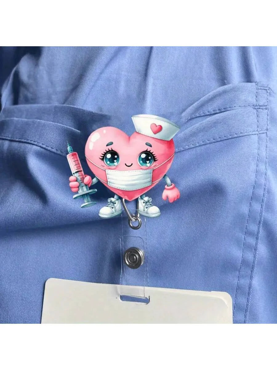 A pink heart-shaped nurse character charm with a stethoscope and ID clip attached to a blue uniform shirt pocket.