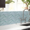 A kitchen countertop with a light blue geometric tile backsplash and a modern faucet.