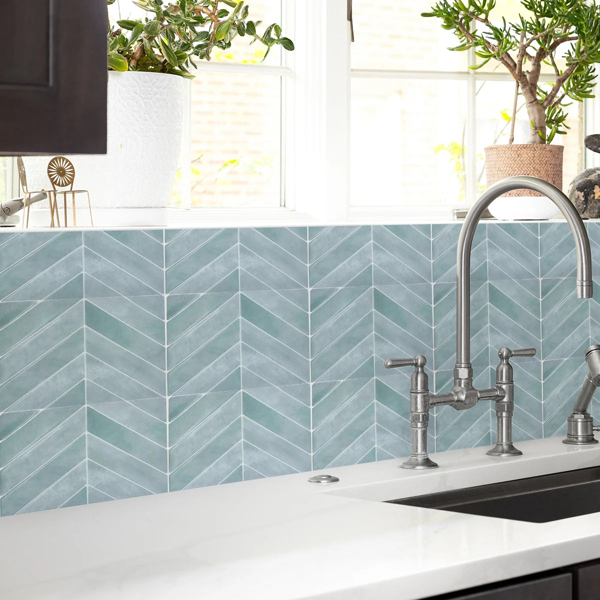 A kitchen countertop with a light blue geometric tile backsplash and a modern faucet.