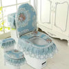 A set of light blue antibacterial toilet seat covers with lace trim and floral embroidery displayed on a white toilet.