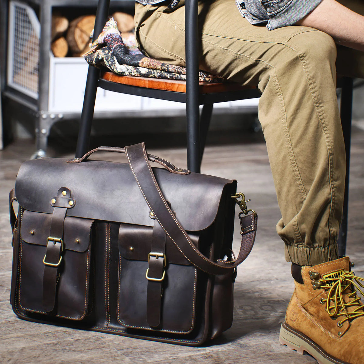 Dunkelbraunes Vintage-Ledertasche auf Holzboden neben einem Bein.