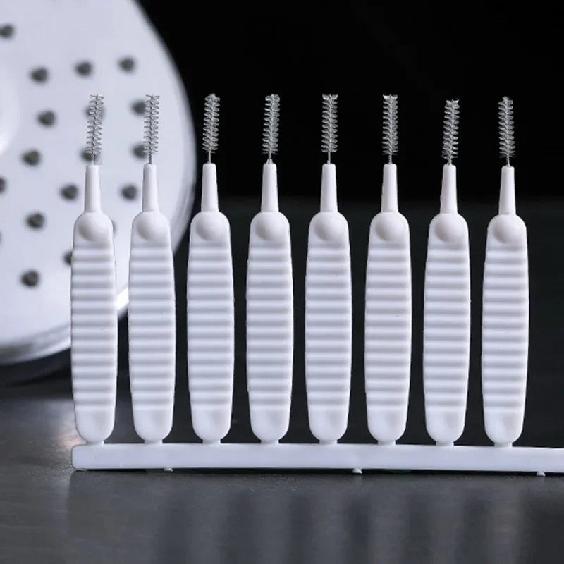A row of white shower cleaning brushes with spiky nozzles displayed on a white tray.