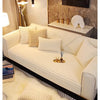 A beige plush anti-slip sofa cushion mat placed on a light-colored sofa with cream pillows and a fluffy rug.