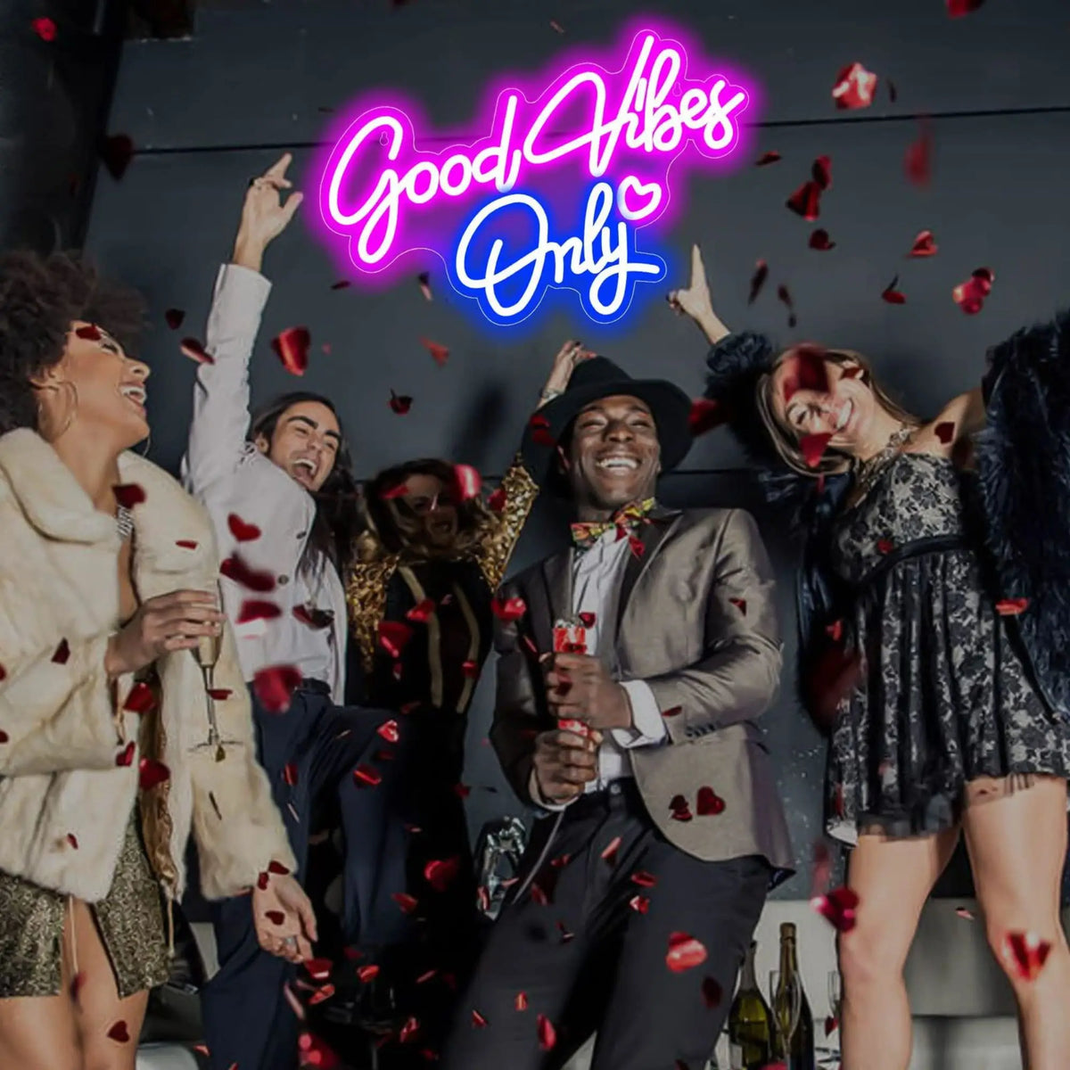 A group of people celebrating with a neon sign that reads Good Vibes Only