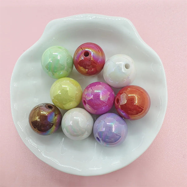 A collection of colorful acrylic beads in various shades including green, pink, yellow, and purple, displayed on a white dish