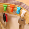 A set of colorful key holder clips and a metal key are displayed on a light yellow bag.