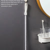 A silver flexible drain cleaning brush hanging on a wall next to a white container.