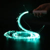 A hand holds an LED fiber optic dance whip, creating a glowing turquoise light swirl in the dark.