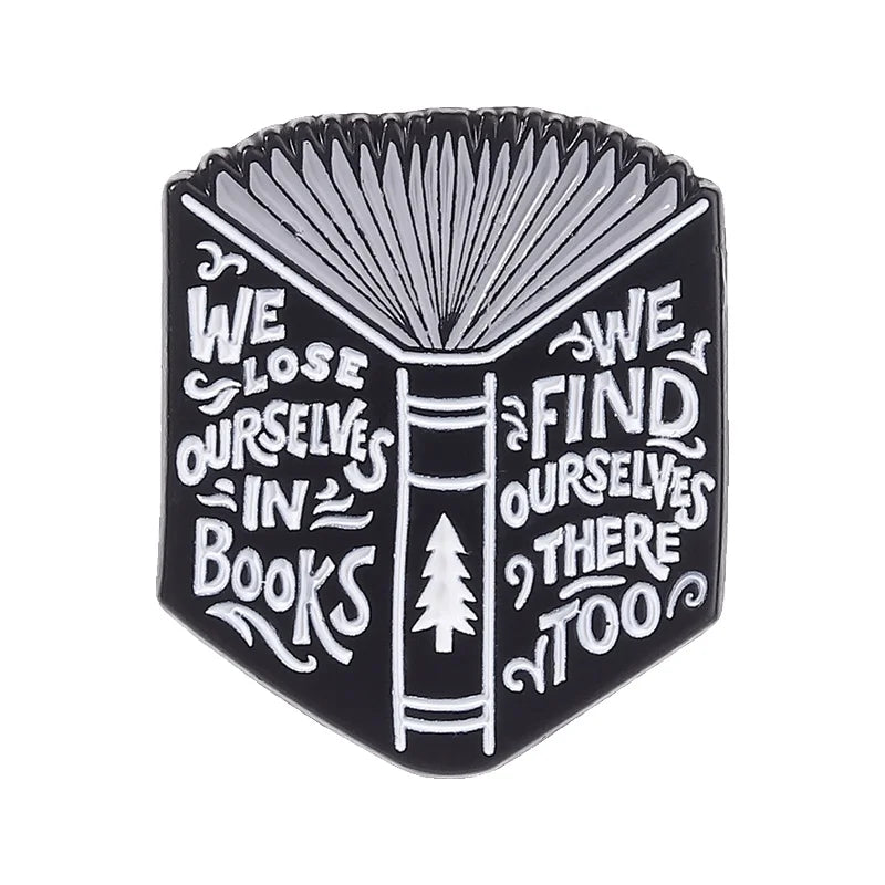 Black enamel pin featuring a stylized open book design with text inside