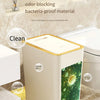 A white pop-up slim trash can with a gold lid is shown next to a toilet, emphasizing its sealed odor-blocking and bacteria-pr