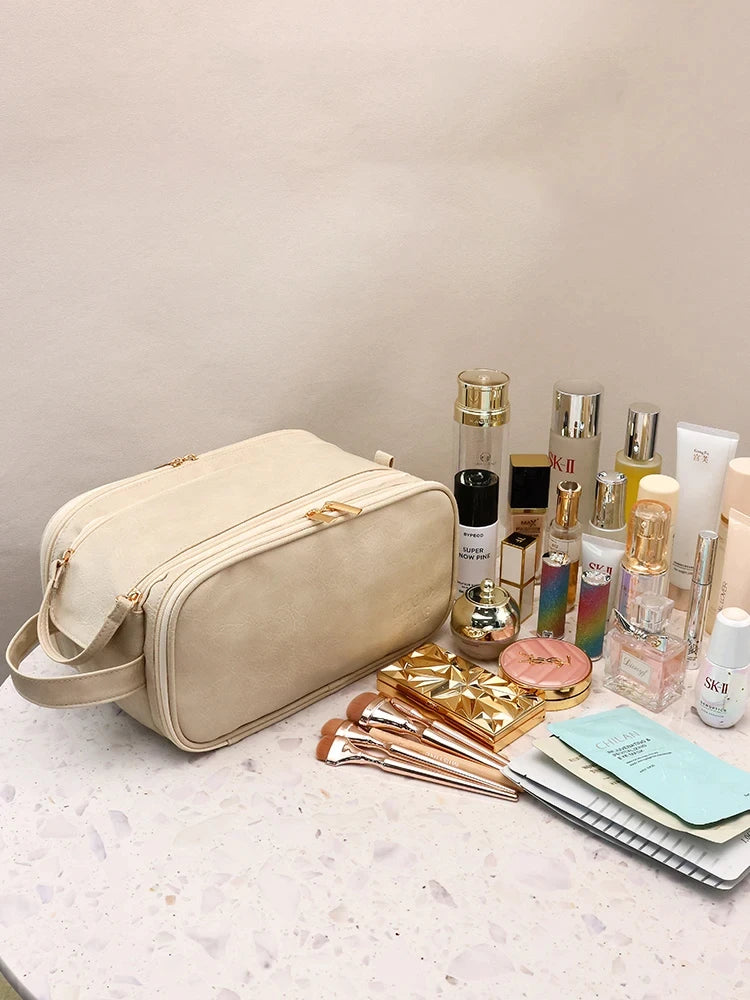 A beige waterproof PU leather cosmetic bag is shown next to various makeup and skincare products on a light surface.