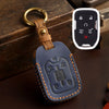 A dark blue leather key fob case with a brass ring attached, resting on a wooden surface next to a white electronic key.