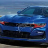 A blue Chevrolet Camaro sports car driving on a road with red trim accents.