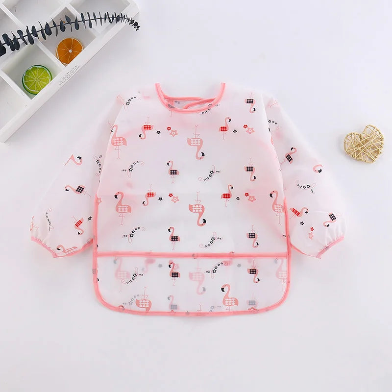A pink waterproof long sleeve smock and feeding bib featuring a pattern of small pink flamingos on a white background.