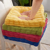 A stack of thick corduroy floor cushions in yellow, green, pink, and blue fabric.