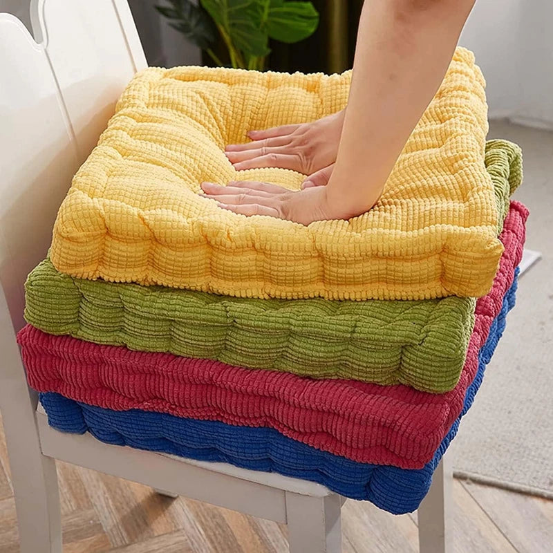 A stack of thick corduroy floor cushions in yellow, green, pink, and blue fabric.