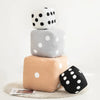 A stack of three soft cube-shaped dice plush pillows in white, gray, and beige with black polka dots.