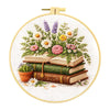 A circular embroidery kit featuring floral designs and stacked books on a white background.