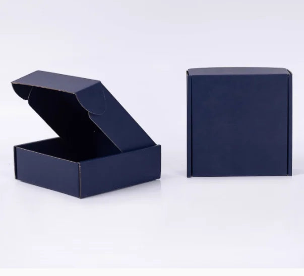 Eine dunkelblaue Wellpappkarton ist geöffnet und eine geschlossene Box daneben zu sehen.