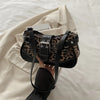 A black leopard print PU leather shoulder bag is being held against a light beige fabric background.