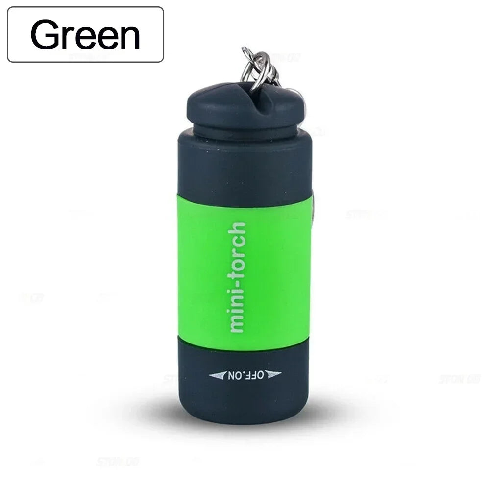 A green mini-torch keychain flashlight with a black body and silver clip.