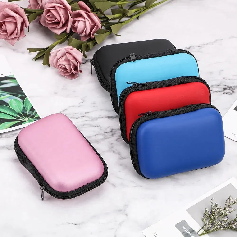 A collection of colorful portable electronics organizer pouches in pink, blue, and red resting on a white marble surface with