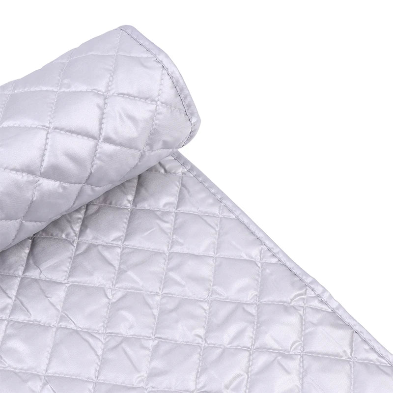 A folded silver quilted ironing mat used for wrinkle removal.