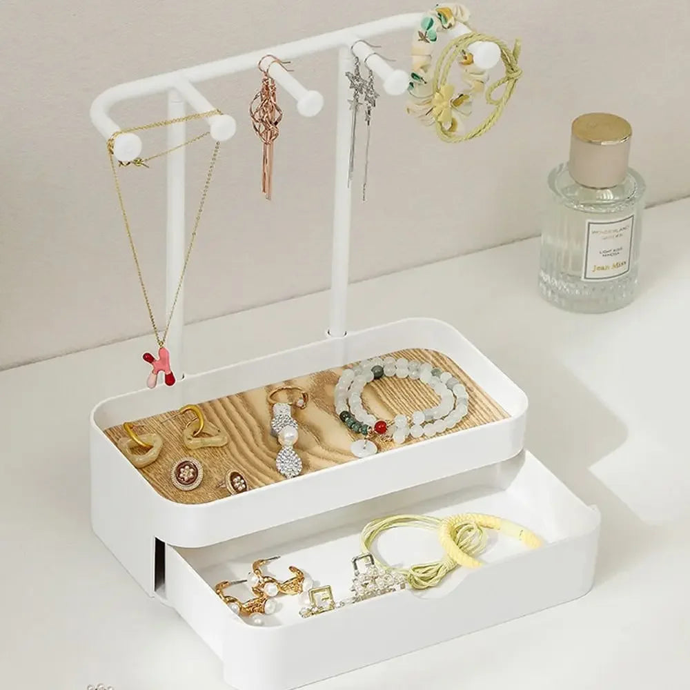 Elegant jewelry display rack featuring a white stand, hanging rods, and a drawer with a wooden base displaying various gold a