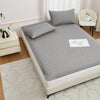 A gray waterproof mattress protector with elastic straps and a quilted pattern is displayed on a bed.