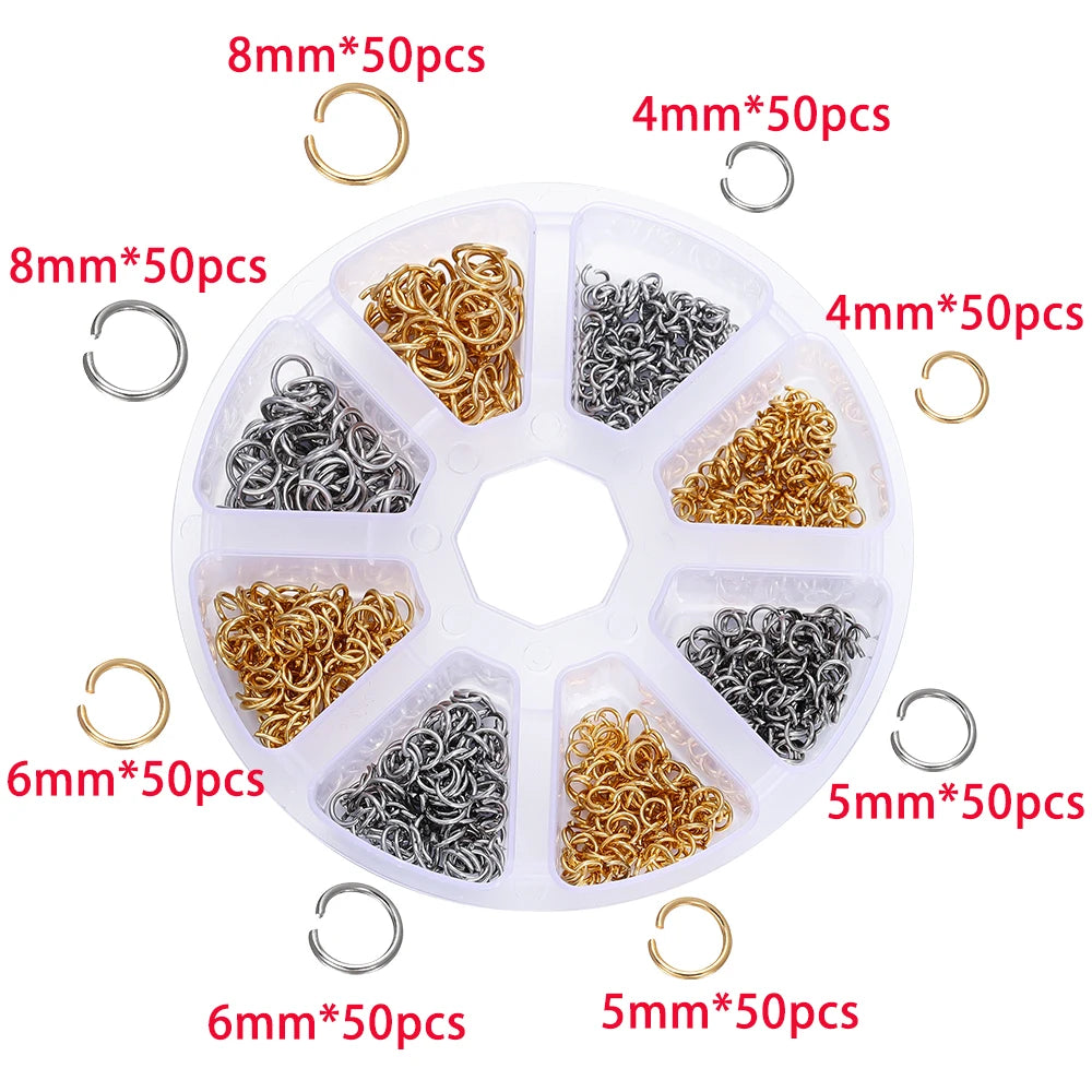 A white tray holds various sizes of gold and silver jump rings and clasps for jewelry making.