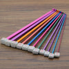 A set of 23 colorful Tunisian crochet hooks with bamboo cables arranged diagonally on a wooden surface.