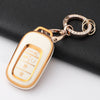 A white Honda key fob cover with gold accents is attached to a silver chain, resting on a black surface.