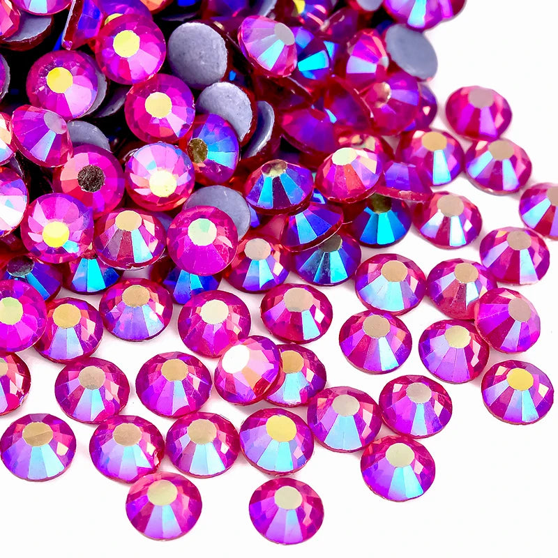 A close-up view of various pink and purple faceted rhinestones scattered on a white background.