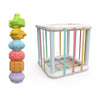 A rainbow-colored shape sorter cube with soft elastic bands used for Montessori learning.