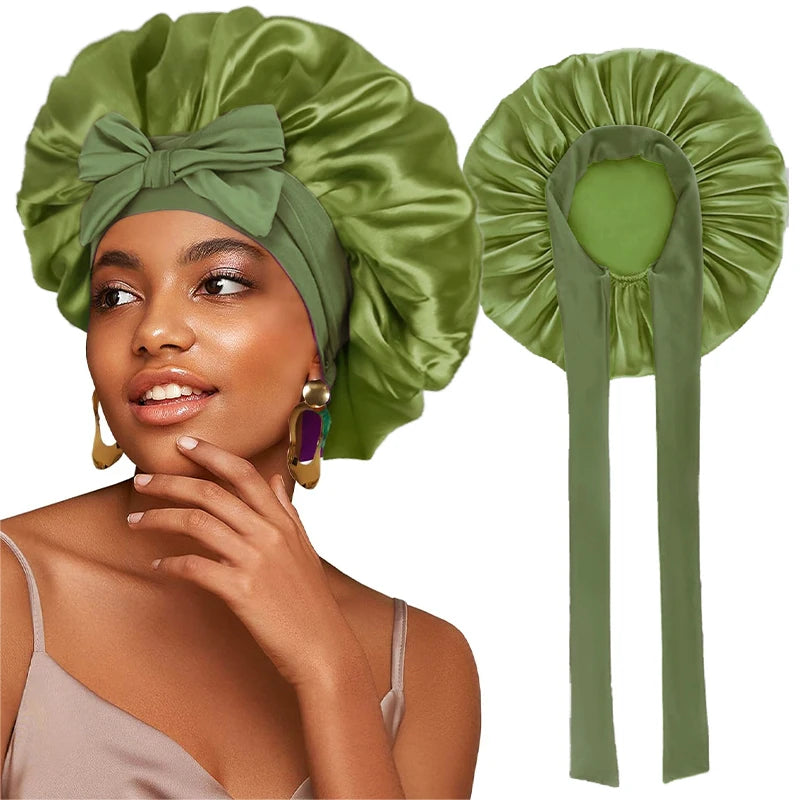 A woman wearing a satin green sleeping bonnet with an adjustable tie and gold earrings.