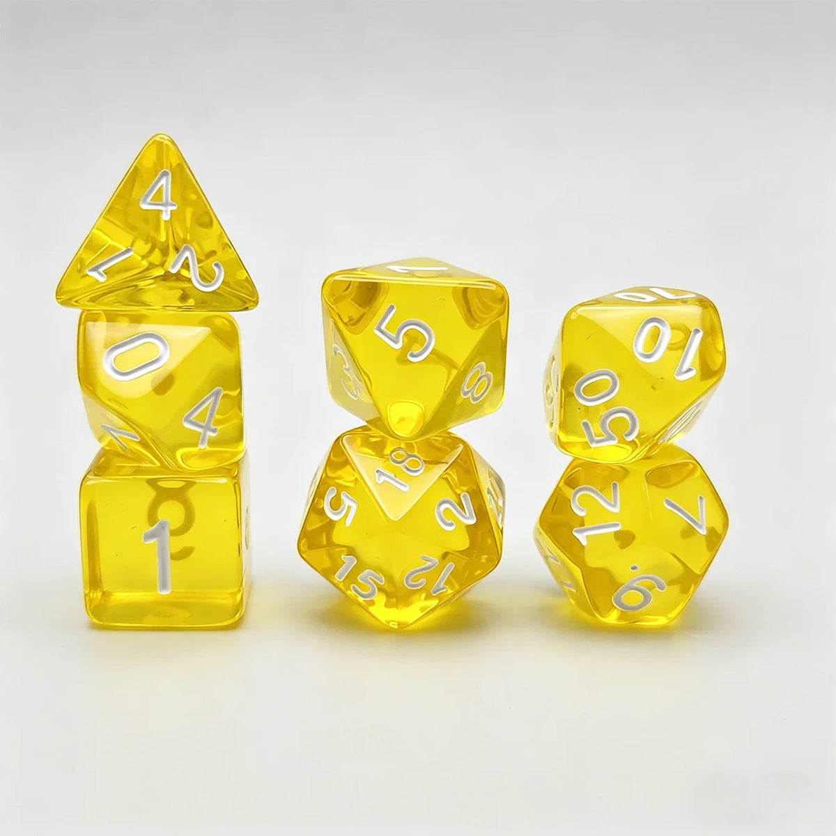A set of seven translucent yellow acrylic polyhedral dice, including a tetrahedron and several dodecahedral dice.