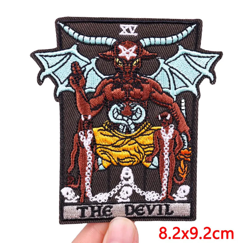 An embroidered patch featuring a demonic figure with horns and bat wings, set against a dark background.