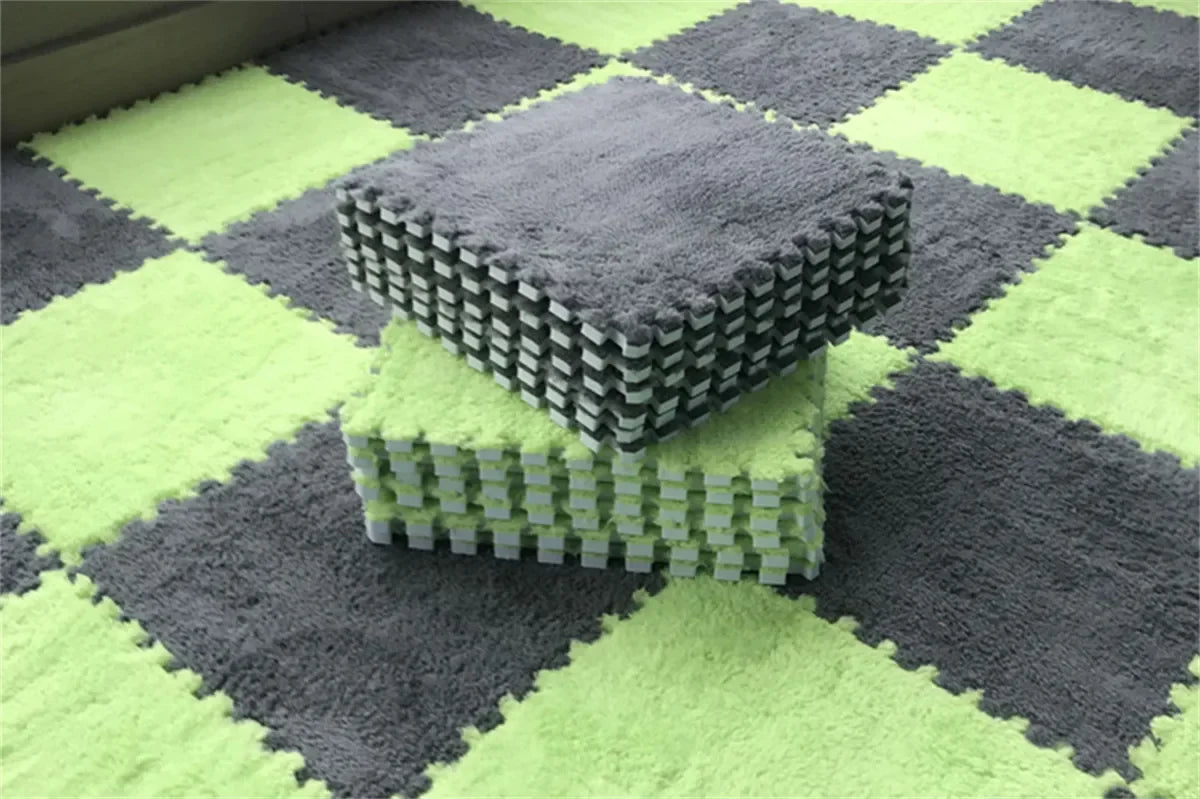 A stack of gray soft plush interlocking floor tiles on a green and gray checkered rug.
