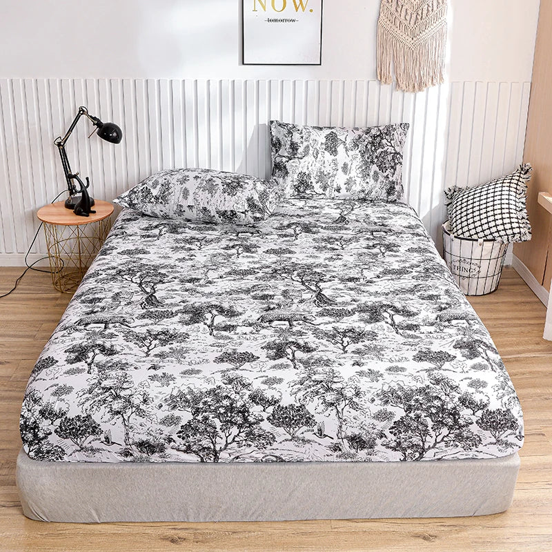 A fitted bed sheet with a marbled print featuring black and white tree motifs is displayed on a bed.