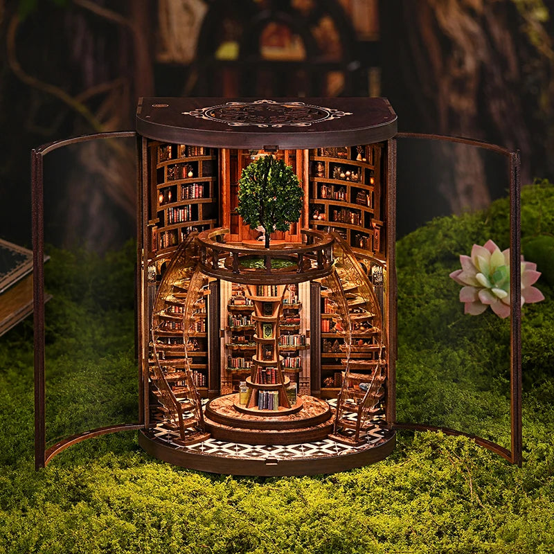A miniature wooden book nook kit featuring shelves, books, and a small tree set in a natural mossy environment.