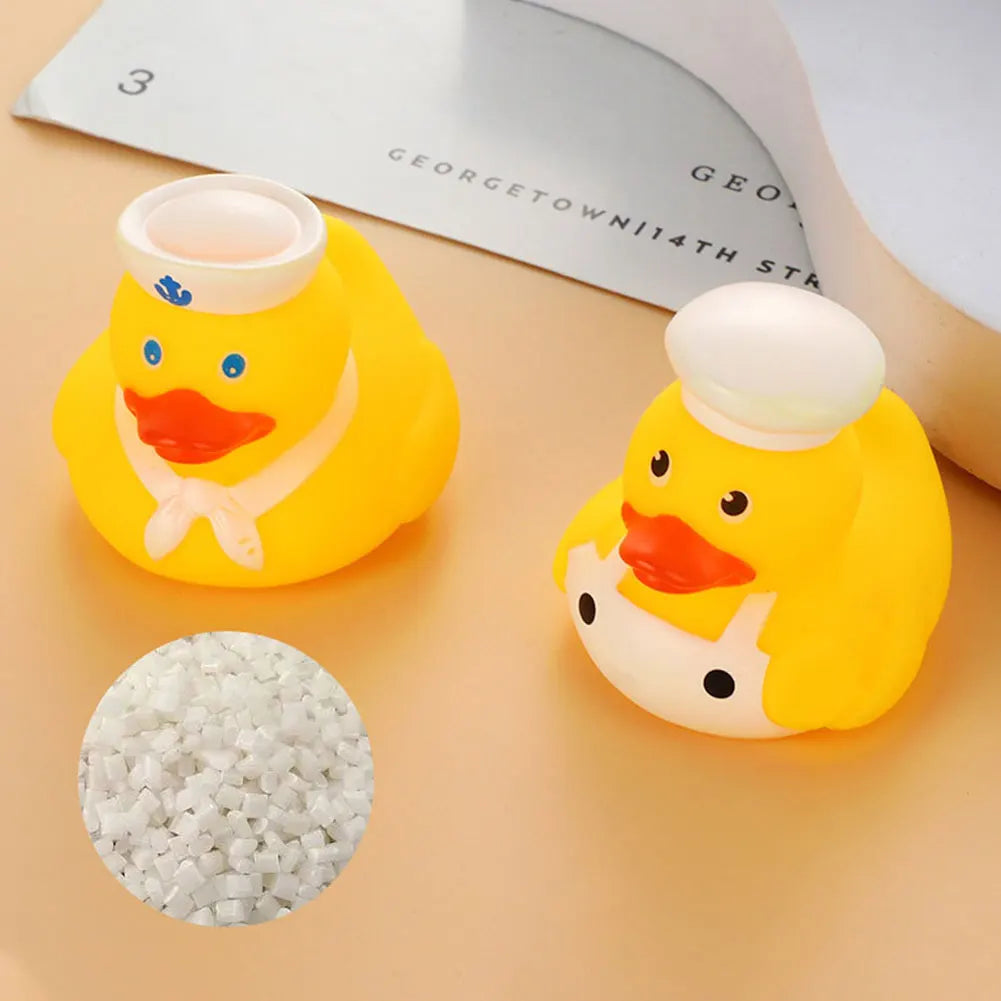 A yellow rubber duck bath toy with an orange beak and white details is shown next to a pile of small white beads.