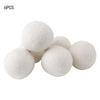 A set of six white natural wool dryer balls shown from above.