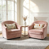 Two pink upholstered armchairs with floral embroidered pillows sit near a window in a bright living room.