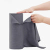 A hand is holding a roll of gray reusable microfiber cleaning towels.