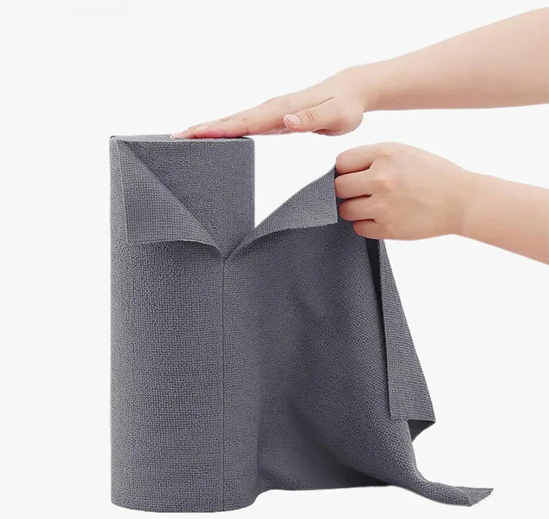 A hand is holding a roll of gray reusable microfiber cleaning towels.