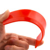 A hand holds a bright red silicone grout and sealant scraper tool, showing its curved shape.