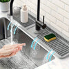 A hand is washing soap and water under a kitchen sink splash guard device.