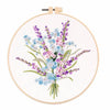 A circular embroidery hoop displaying a bouquet of purple, blue, and pink wildflowers.